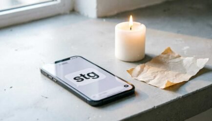 Text: "Smartphone displaying 'stg' text message next to a lit candle on a minimalist desk"