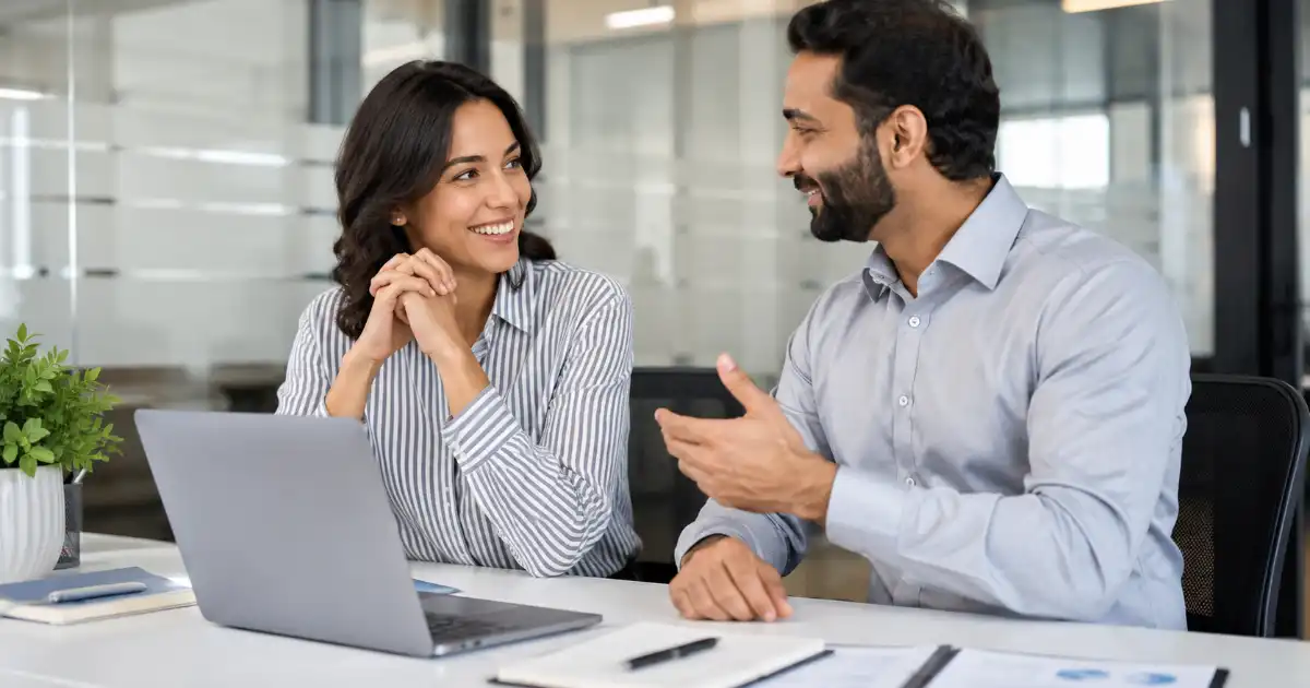 Two diverse professionals sharing positive feedback and encouragement during a successful workplace discussion