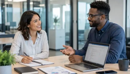 Two diverse professionals having a helpful workplace conversation while sharing information and offering assistance.